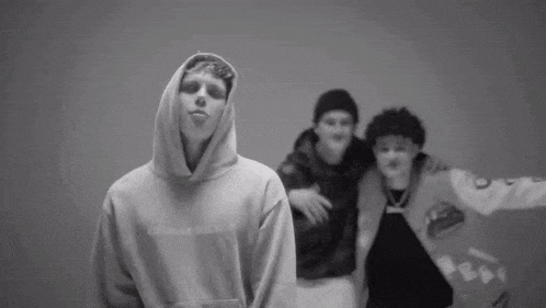 a man in a hoodie is standing next to two other men in hoodies .