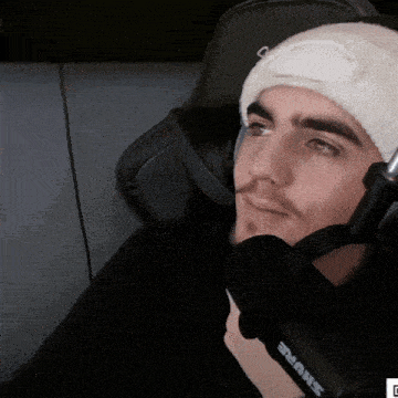 a man wearing headphones and a white beanie is holding a shure microphone
