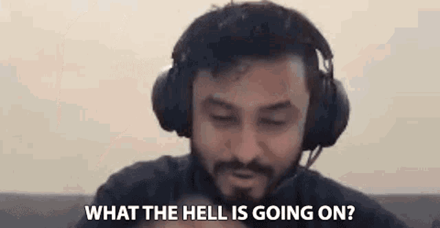 a man with a beard and headphones is sitting on a couch and talking .