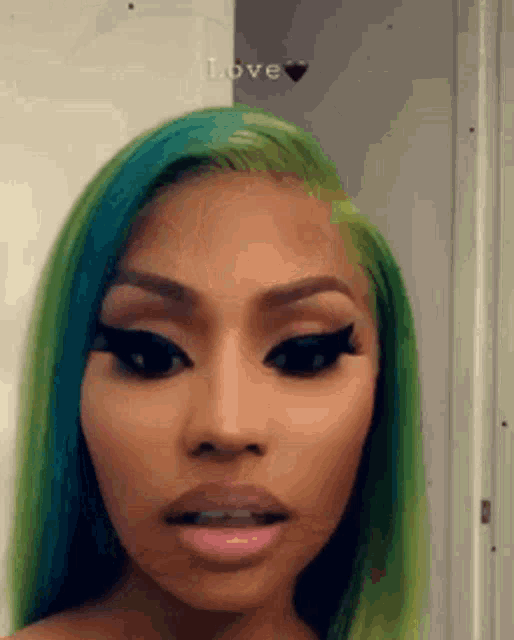 a close up of a woman 's face with green hair and black eyeliner .