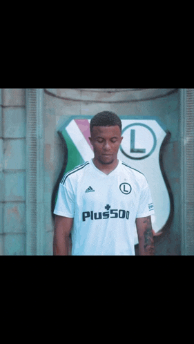 a man wearing a white adidas shirt with the letter l on it