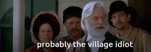 a man with a beard stands in front of a group of people with the words probably the village idiot above him