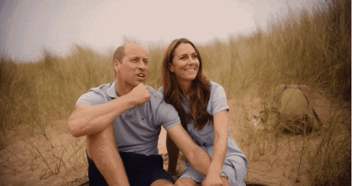 a man and a woman are sitting on a sandy field