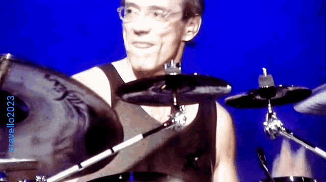 a man playing drums with a blue background and the number 2023 on the bottom right