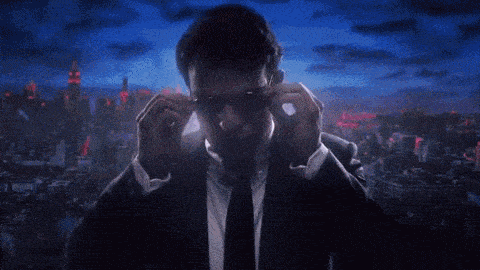 a man in a suit and tie adjusting his sunglasses