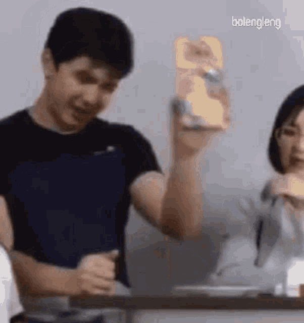 a man is holding a box of cereal while standing next to a woman .