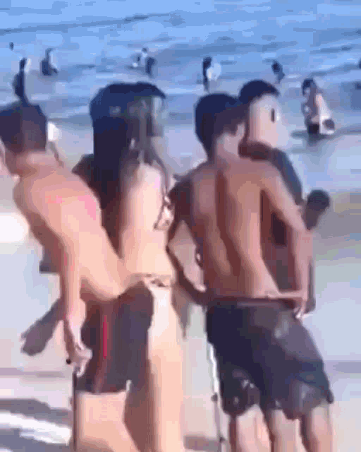 a group of people standing on a beach looking at the water .