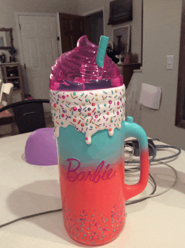 a barbie mug with sprinkles on it and a straw