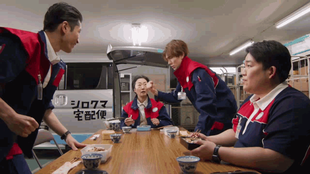 a group of people sitting at a table in front of a van with chinese writing