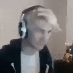 a man wearing headphones and a hat is sitting in front of a computer screen .