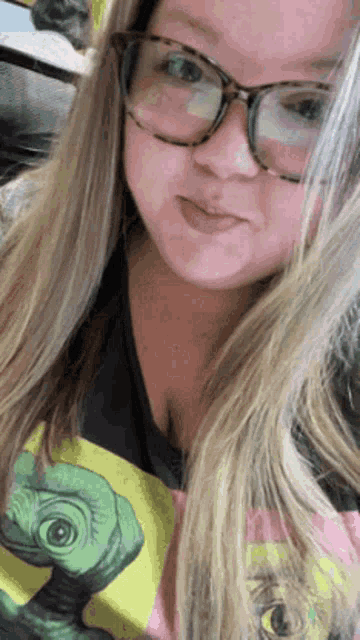 a woman wearing glasses and a t-shirt with a picture of an alien on it .