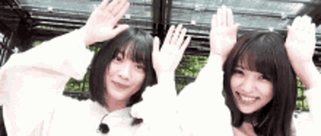 two young women are waving their hands in the air .