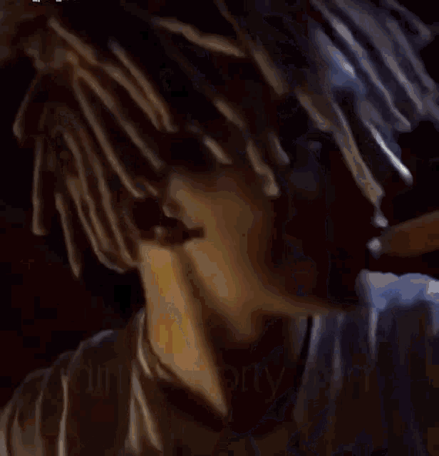 a person with dreadlocks is sitting in a room with a lamp in the background .