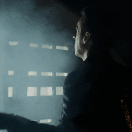 a man in a black jacket looks out a window