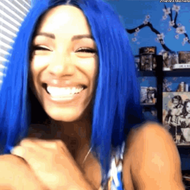 a woman with blue hair is smiling in front of a window