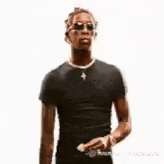 a man is walking down a runway at a fashion show wearing sunglasses and a black shirt .