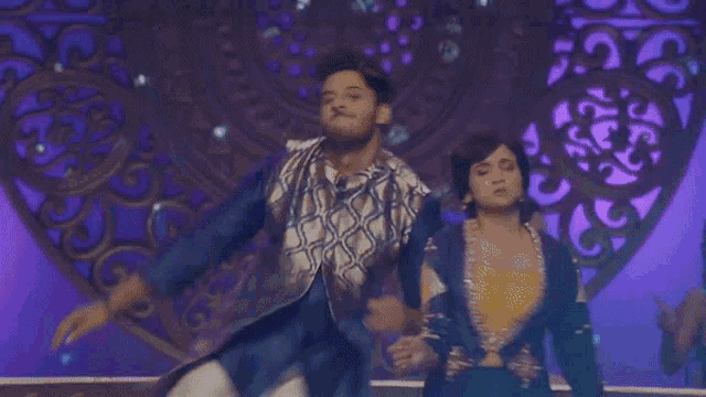 a man and a woman are dancing together in front of a purple background .