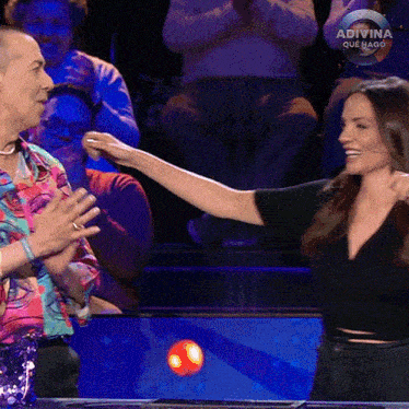 a woman reaches out to a man on a show called adivina