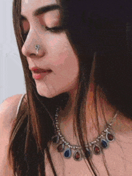 a close up of a woman wearing a nose ring and necklace .