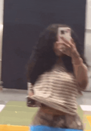 a woman is taking a picture of herself in the mirror with her phone .