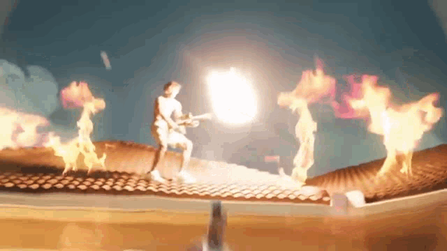 a man is playing a guitar on top of a roof with flames coming out of it
