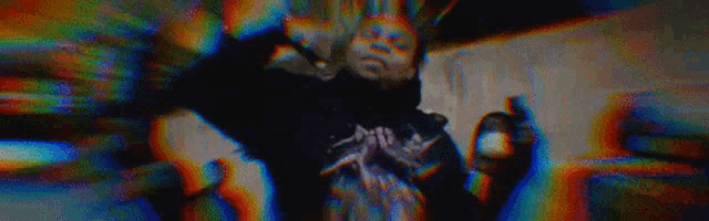 a man is singing into a microphone in a blurry video with a colorful background .