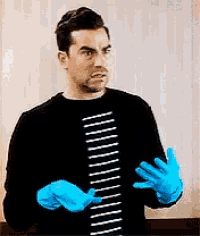 a man wearing a black shirt and blue gloves is making a funny face .