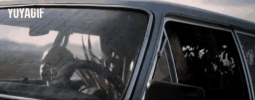a man is driving a car with the word yuyagif on the bottom right corner .