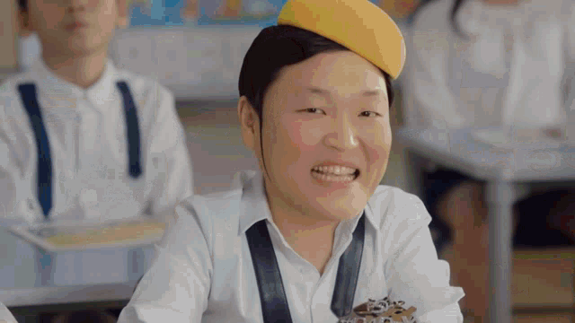a man wearing a yellow hat and a tie smiles in a classroom