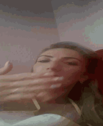 a woman is covering her mouth with her hands in a blurry photo