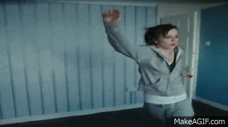 a woman is dancing in a room with a blue wall .