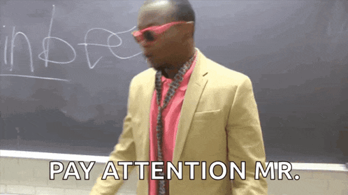 a man standing in front of a blackboard with the words pay attention mr.