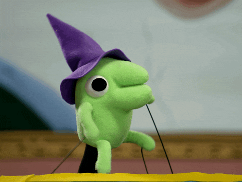 a green stuffed animal with a purple hat on it
