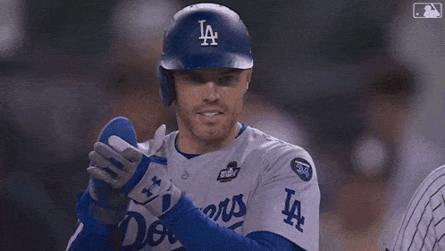 a baseball player is wearing a dodgers uniform and gloves while standing on the field .