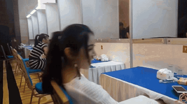 a woman sits at a table with the number 7 on the wall