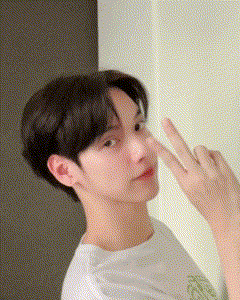 a young man is making a peace sign with his fingers .