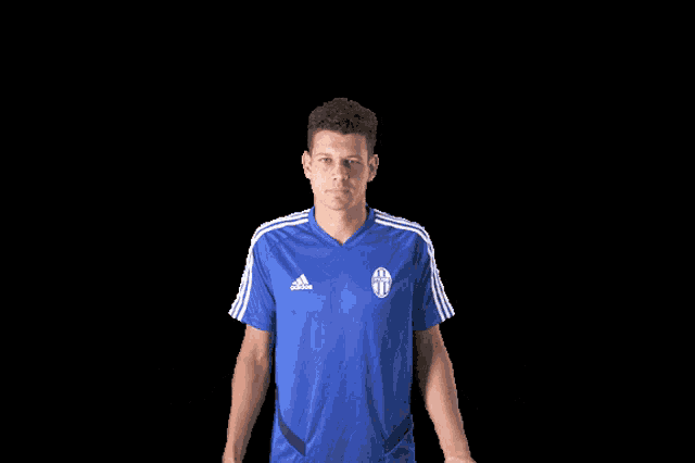 a man wearing a blue adidas shirt is shrugging