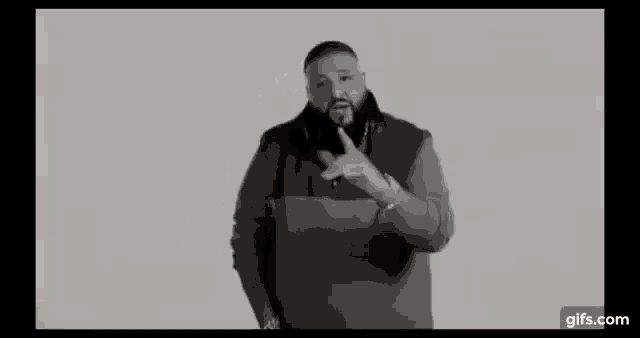 a black and white photo of a man holding a microphone and giving a thumbs up .