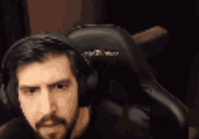 a man with a beard is wearing headphones while sitting in a chair .