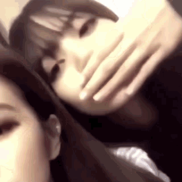 two girls are taking a picture of themselves with their hands over their mouths .