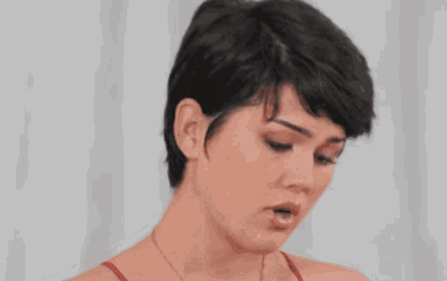 a woman with short hair is wearing a red tank top and smiling