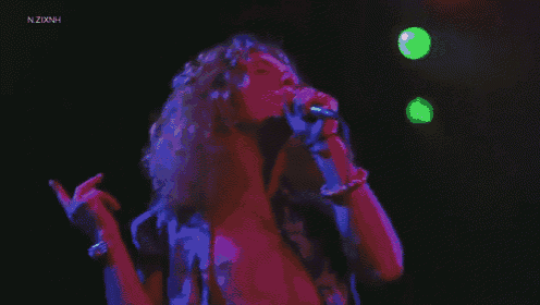 a woman is singing into a microphone on stage .
