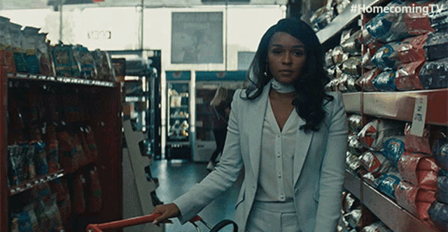 a woman in a white suit is pushing a shopping cart in a store