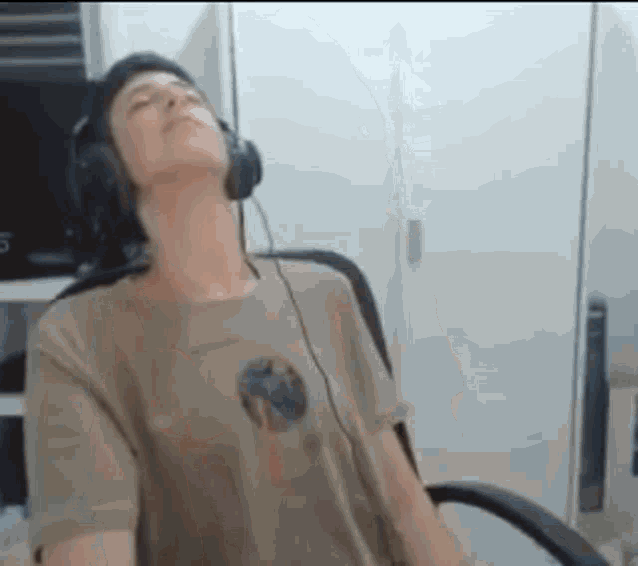 a man is sitting in a chair wearing headphones and a t-shirt .