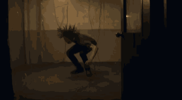 a man in a black shirt is jumping in the air in a dark room