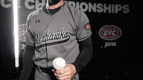 a man holding a baseball in front of a sign that says championships