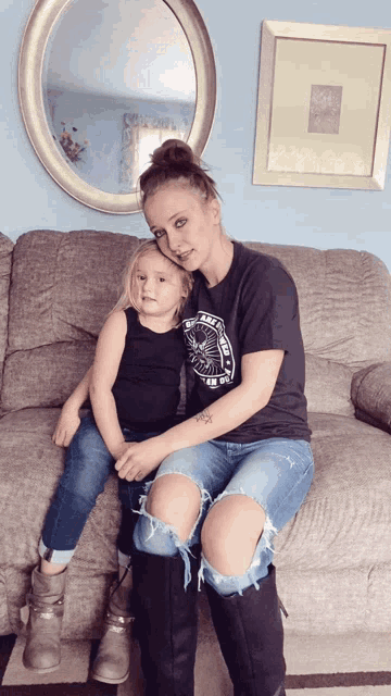 a woman sitting on a couch holding a little girl who is wearing a shirt that says i 'm on