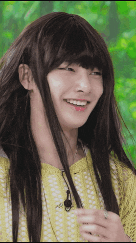 a woman with long hair and a yellow shirt smiles