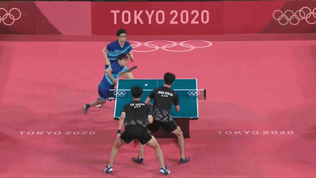 two men are playing ping pong on a tokyo 2020 court