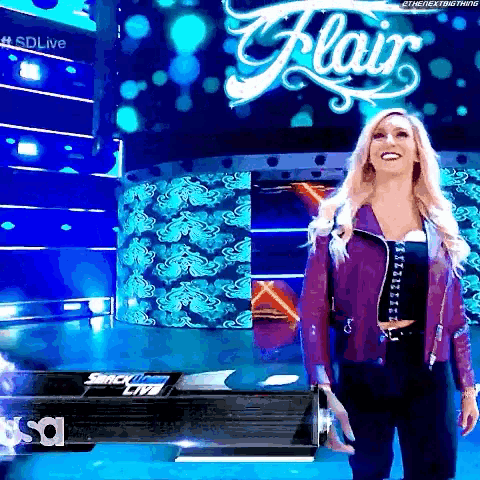 a blonde woman in a purple jacket is standing in front of a sign that says flair